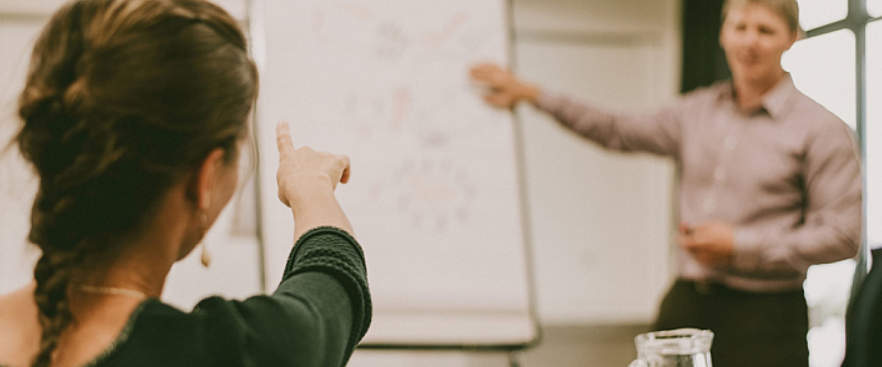 Účastnice školení ukazuje na flipchart a diskutuje s lektorem během praktického kurzu facilitace od Edutica.